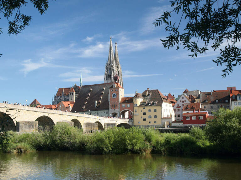 Eine malerische Steinbrücke überspannt den Fluss vor der Altstadt von Regensburg.